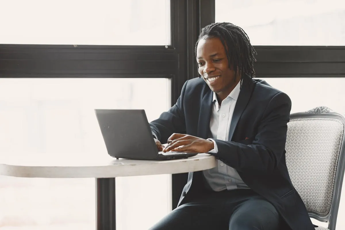 Dono de negócio iniciante sorrindo ao usar notebook pela primeira vez, ambiente de trabalho organizado