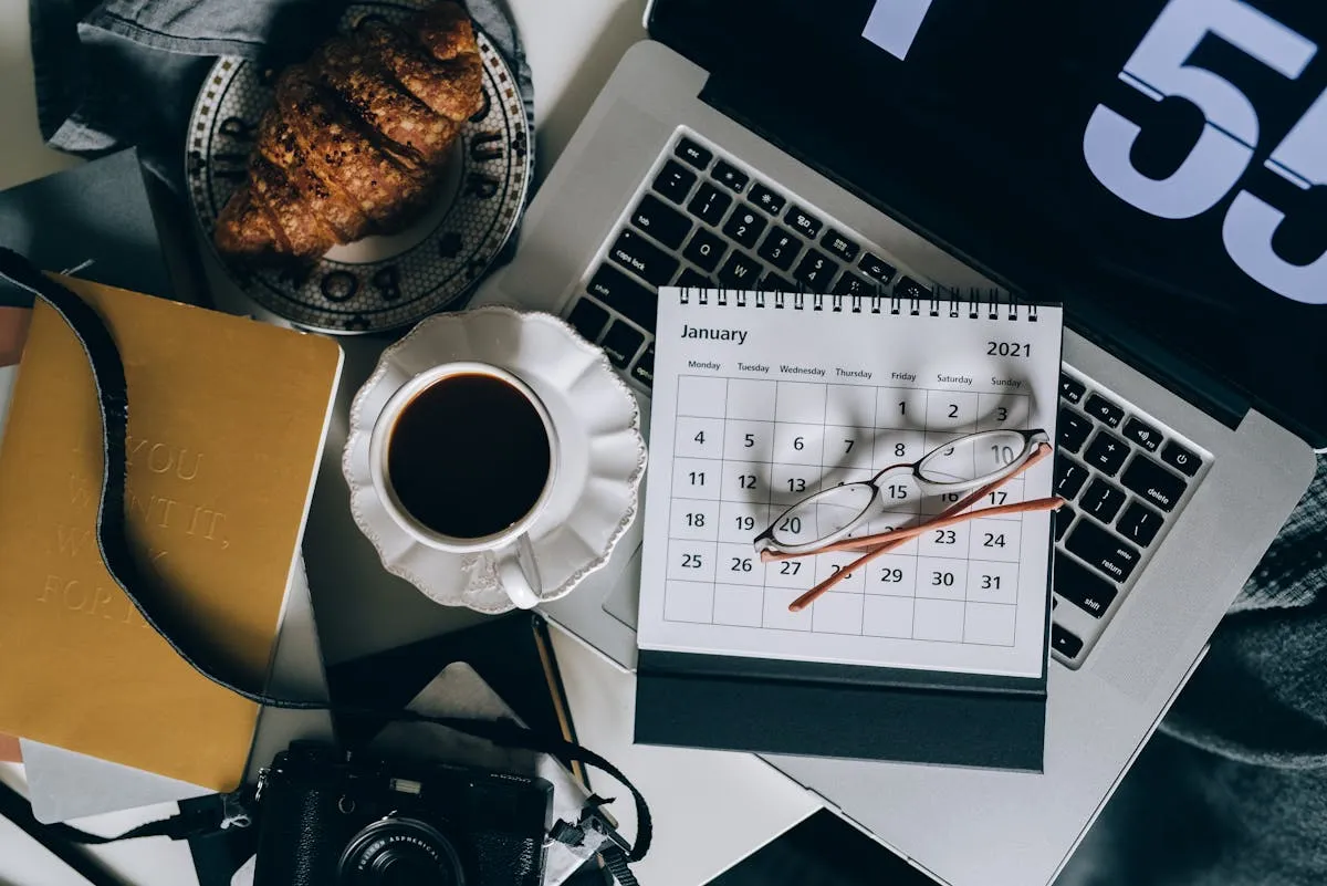Empresário olhando para calendário ao lado de laptop aberto