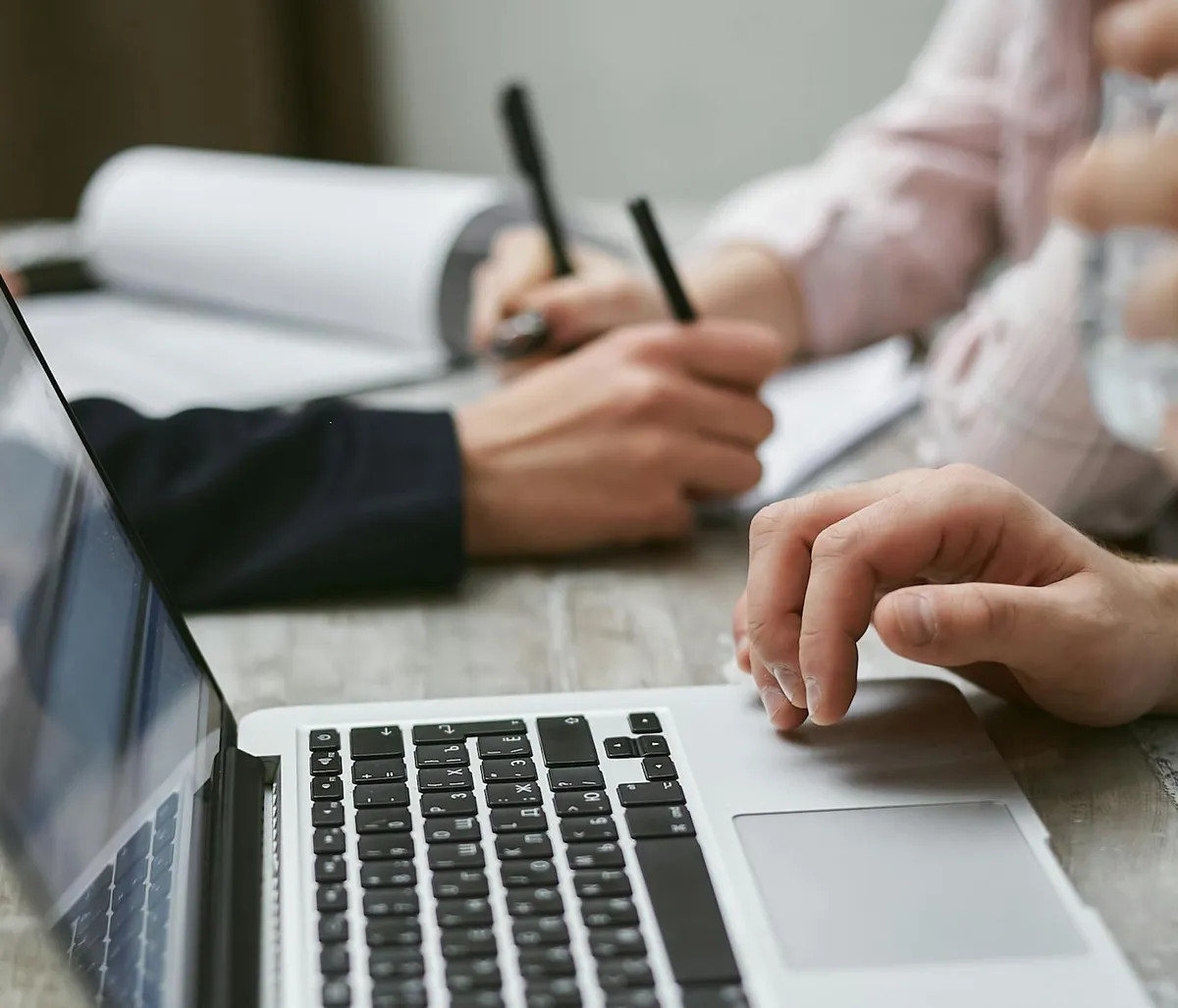 Empresário digitando em laptop com anotações na mesa, configurando sistema de IA
