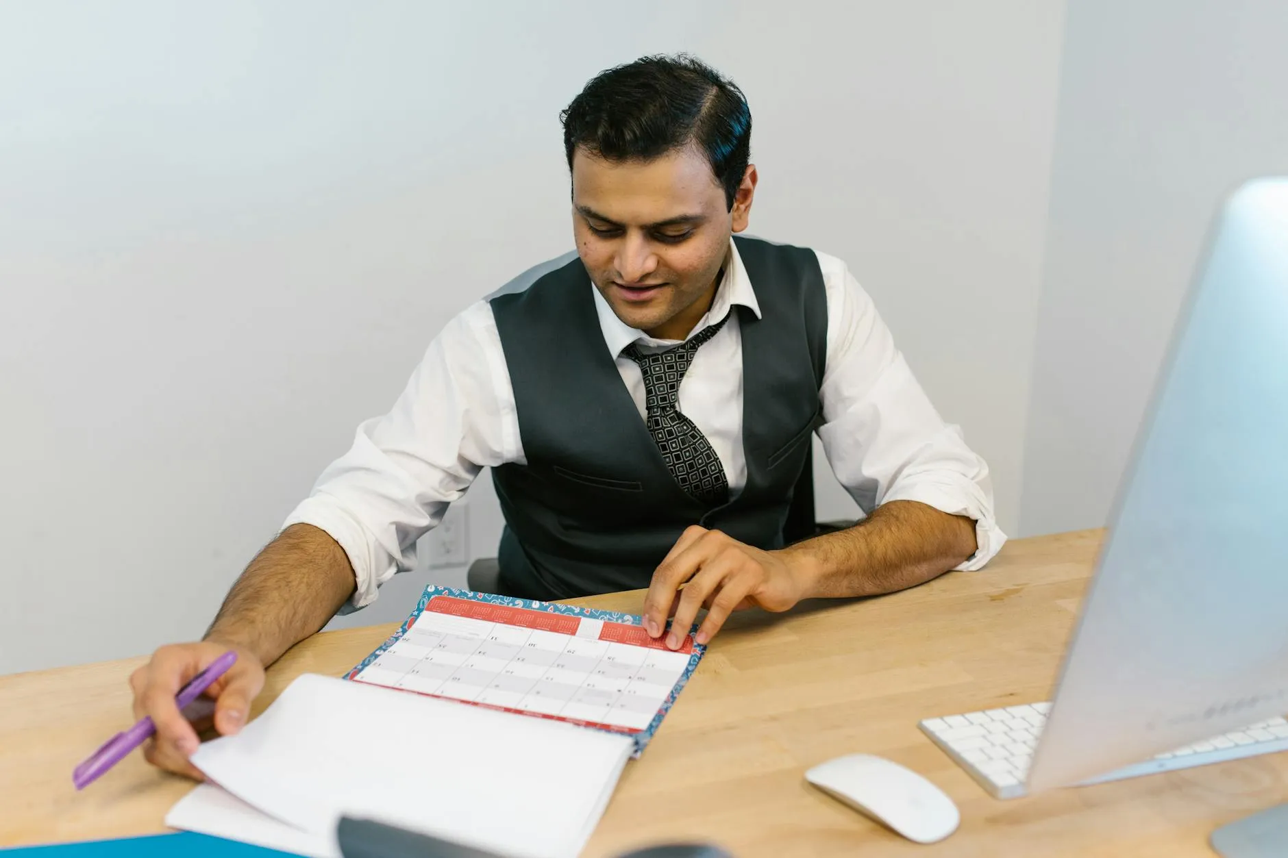 Empresário planejando a semana num caderno com calendário na mesa