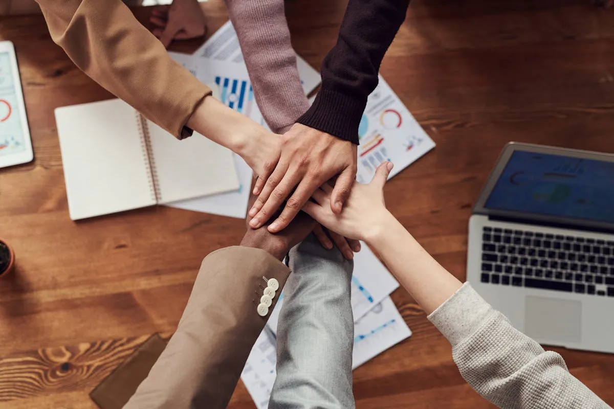 Dono de empresa e equipe reunidos em torno de mesa de trabalho, discussão produtiva