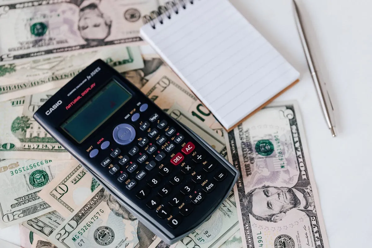 Empresário calculando custos no computador com caderneta ao lado