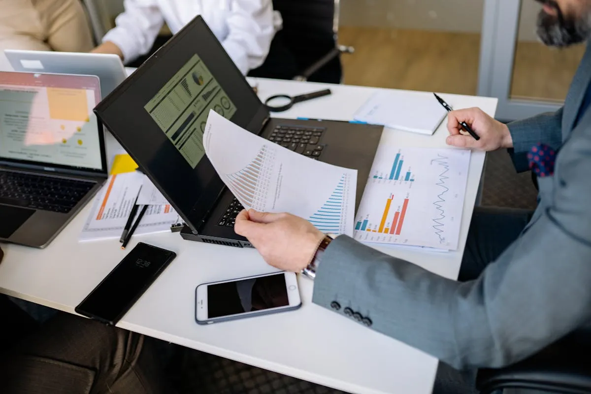Empresário analisando planilha de custos ao lado de um computador