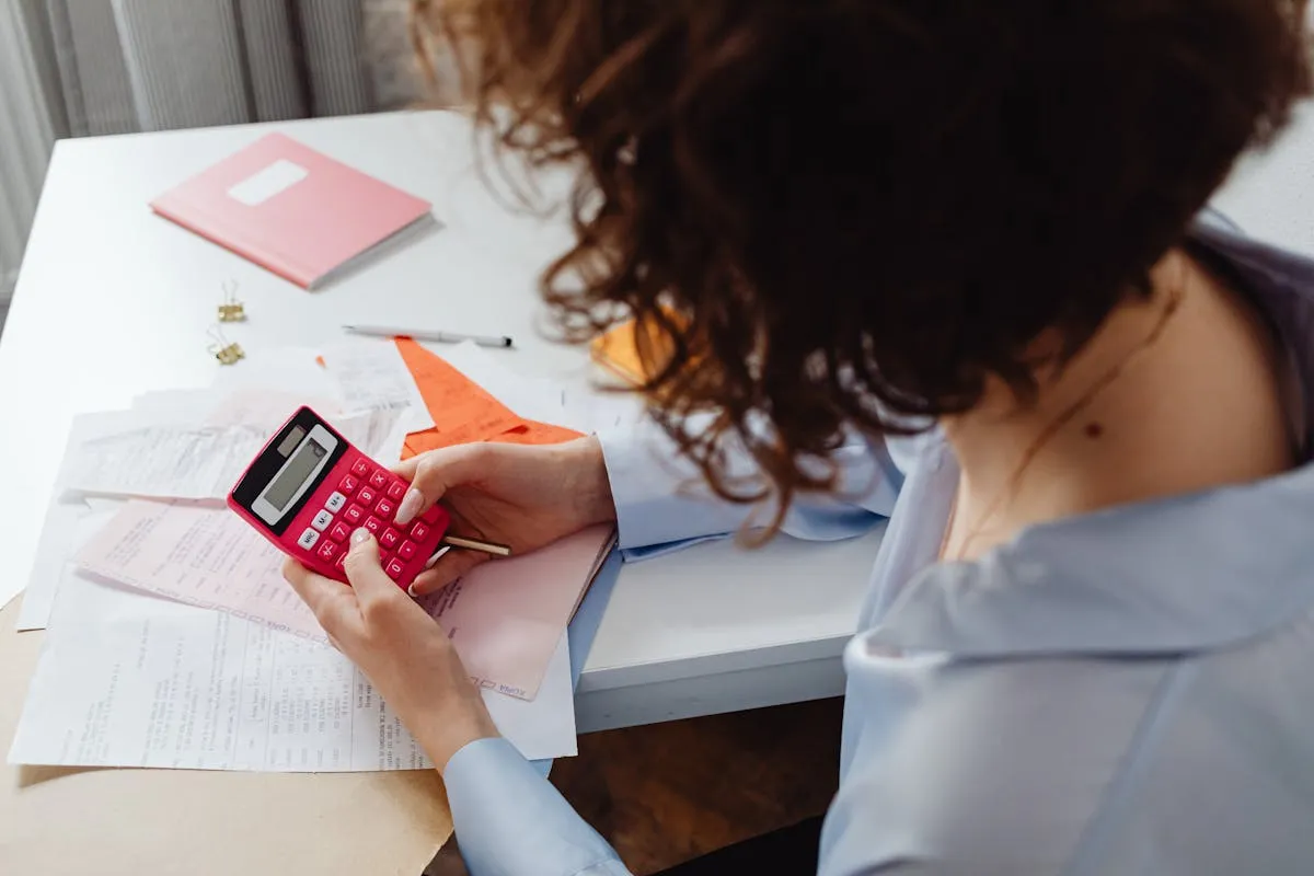 Dono de negócio calculando custos com caderno e calculadora na mesa