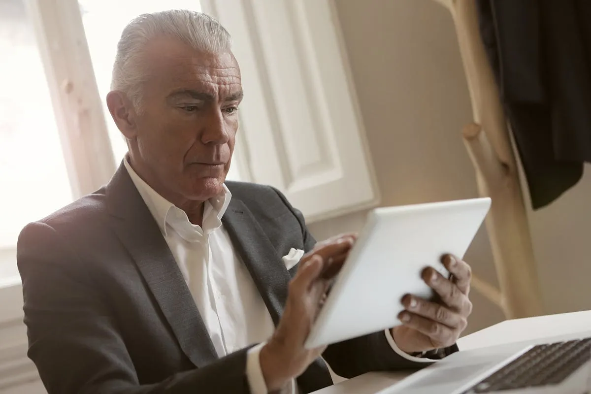 Empresário mais velho sorrindo ao usar tablet em mesa de trabalho